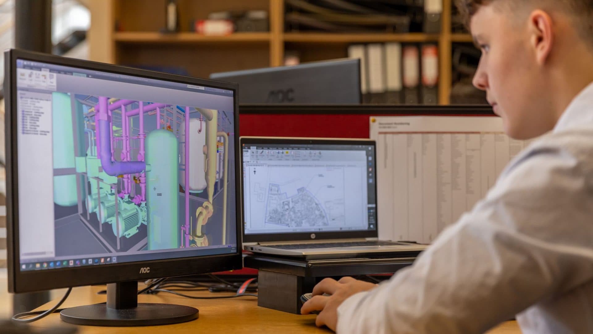 Engineer working on a 3D CAD model across two monitors