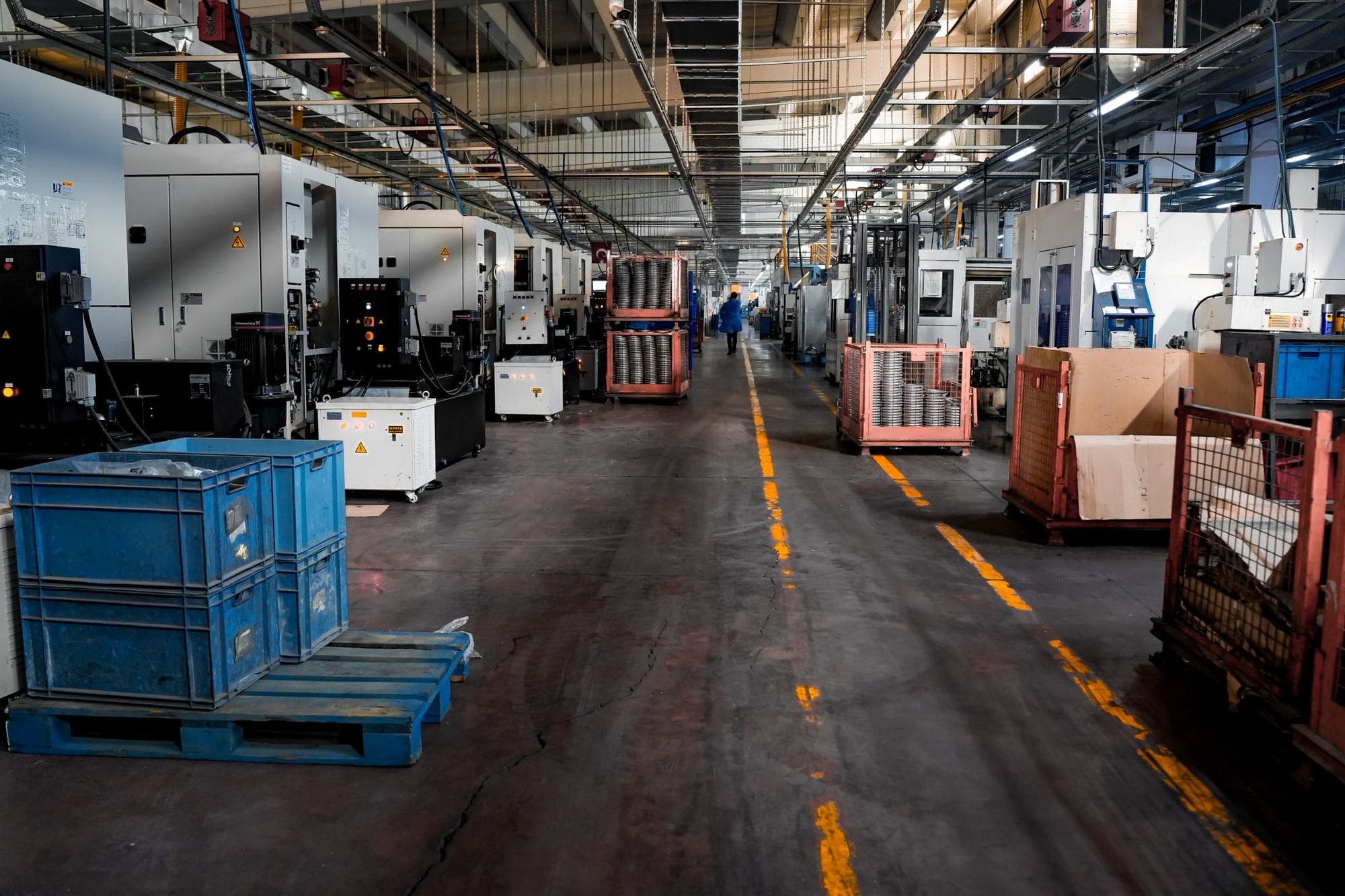 Corsia di un reparto di lavorazioni CNC con cassette di componenti e macchine utensili ai lati