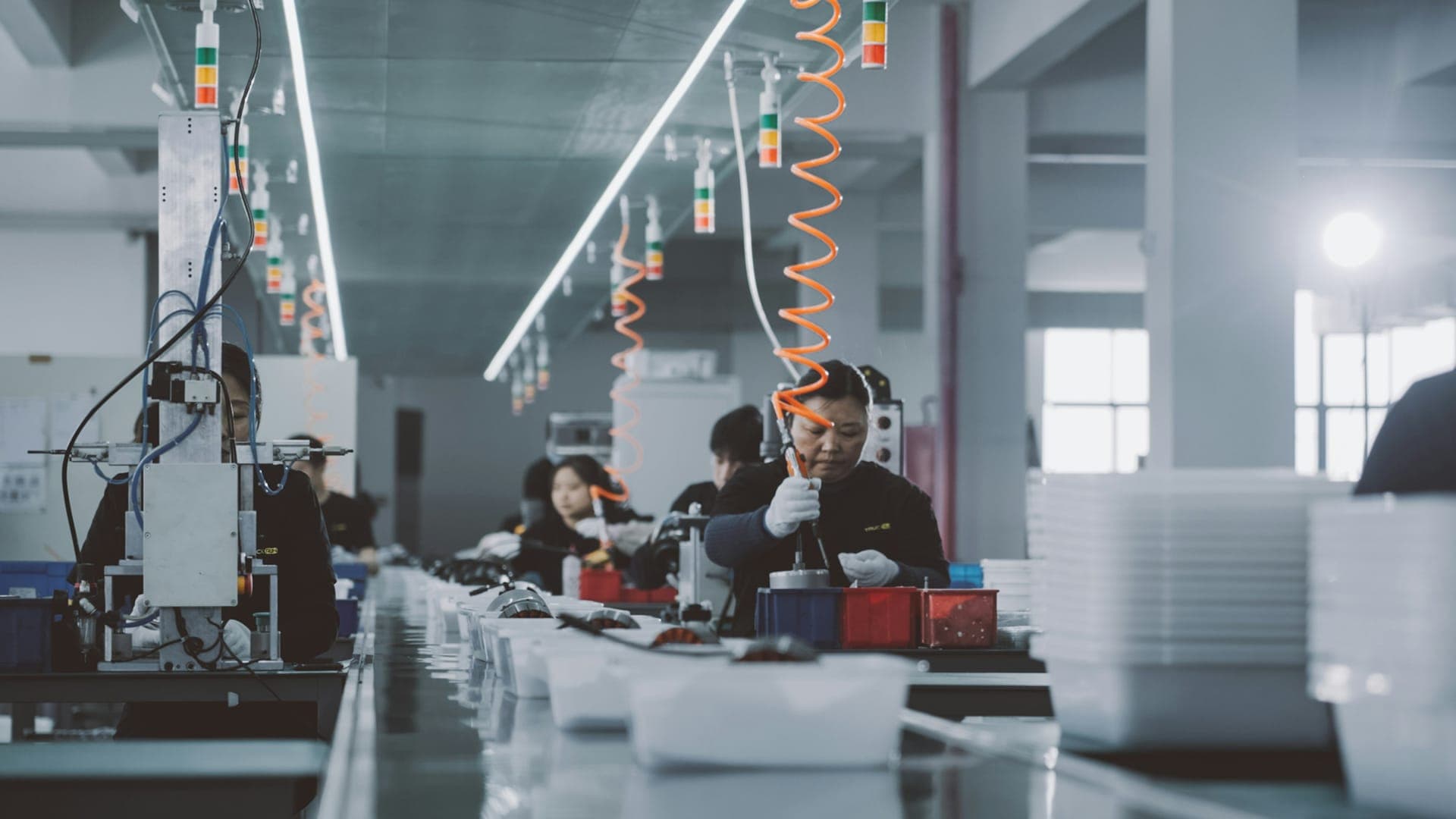 Operators at an assembly line fitting components from trays