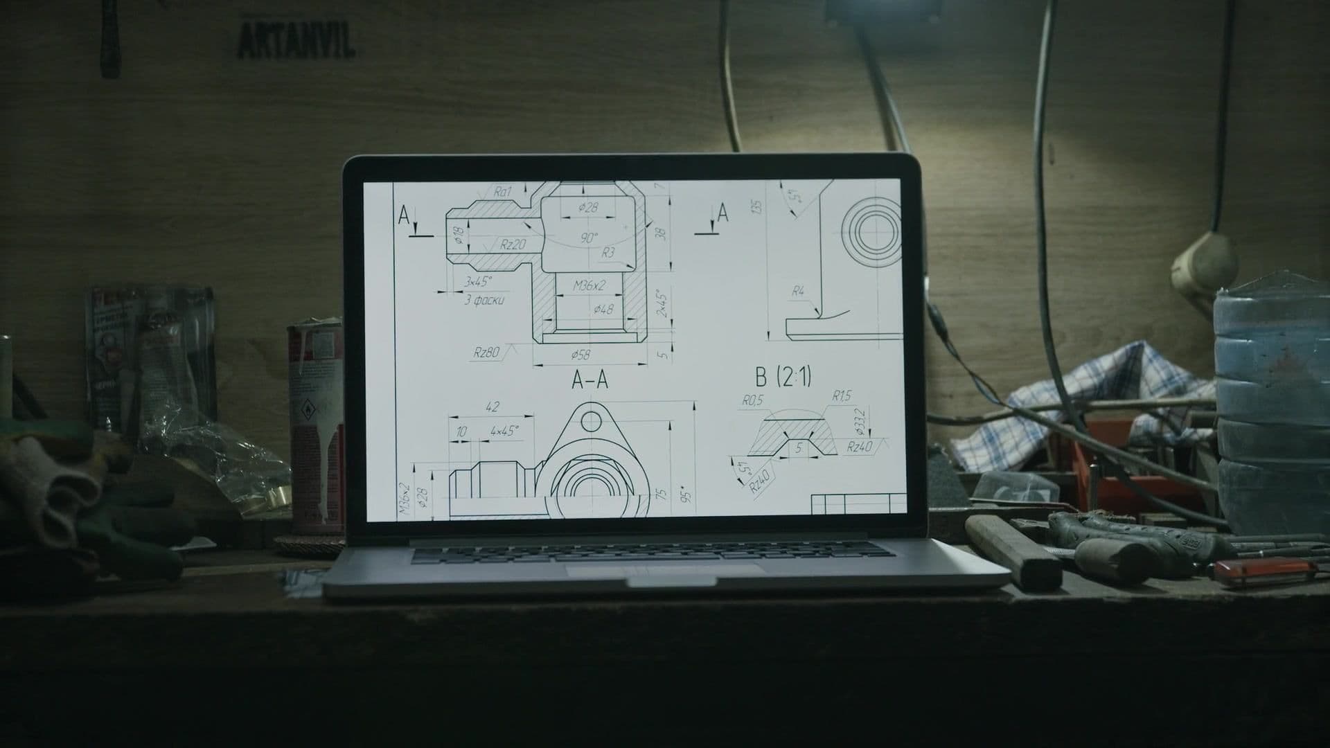 Technical drawing with section views open on a laptop in a workshop