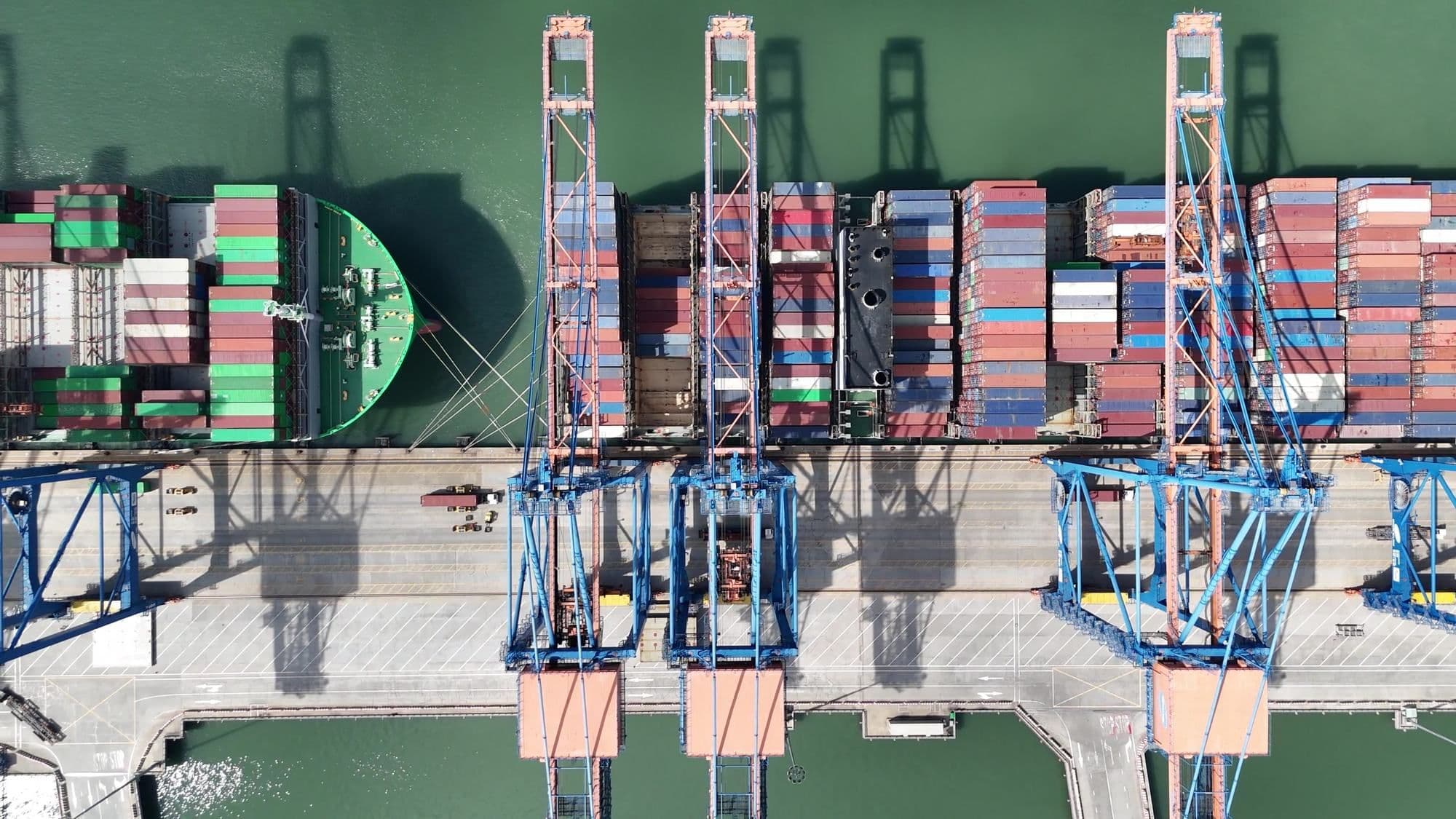 Aerial view of a container ship being loaded by gantry cranes at a port terminal
